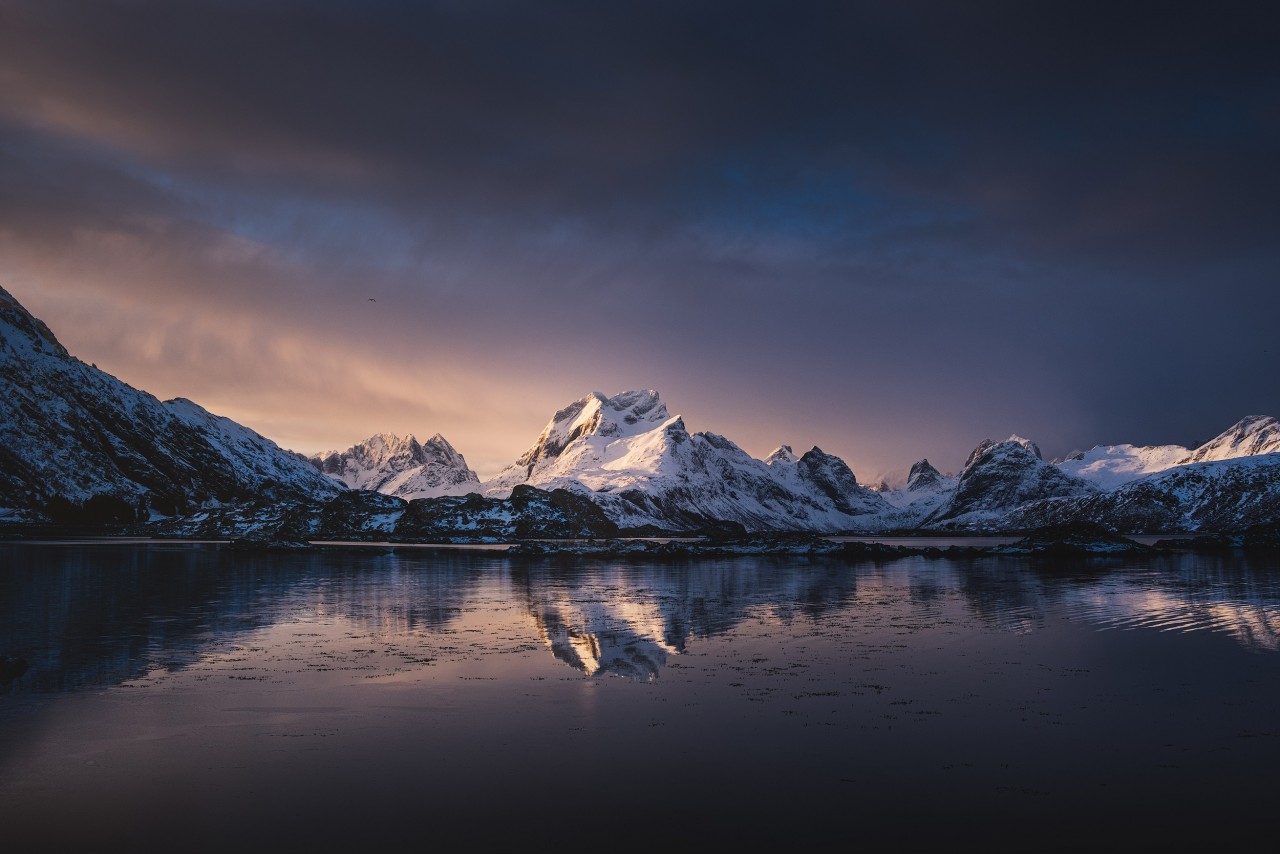 Das schneebedeckte skandinavische Gebirge, welches sich im Meer wiederspiegelt