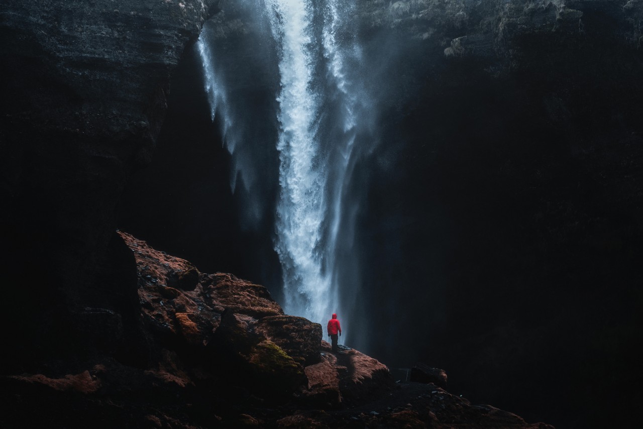 Langzeitbelichtung in Norwegen mit Kvernufoss Wasserfall im Hintergrund und Felsen im Vordergrund