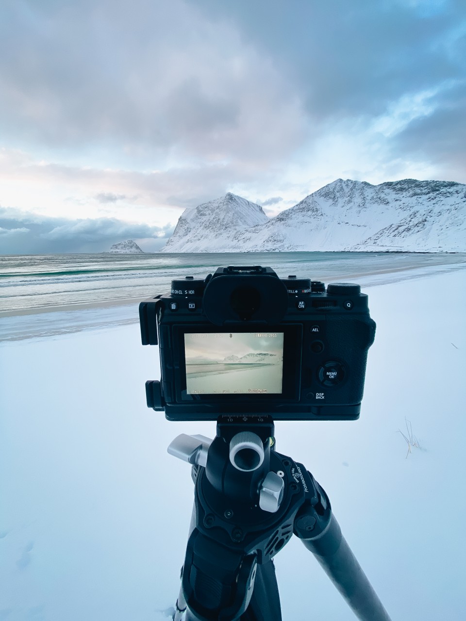 Kamera und Stativ vor einer verschneiten Küste